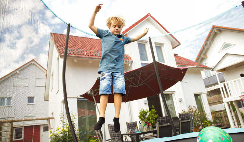 Junge springt auf dem Trampolin im Garten von Familie Wenzel