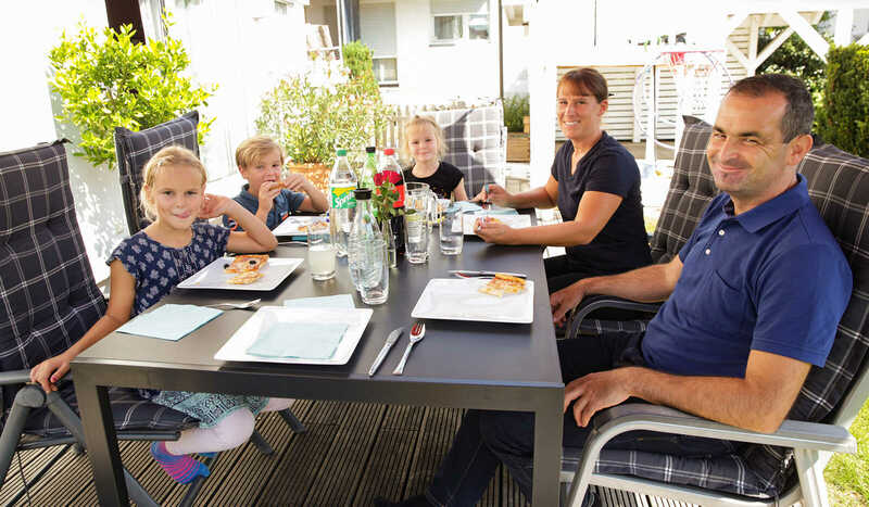 Familie Wenzel sitzt am Gartentisch und isst Pizza